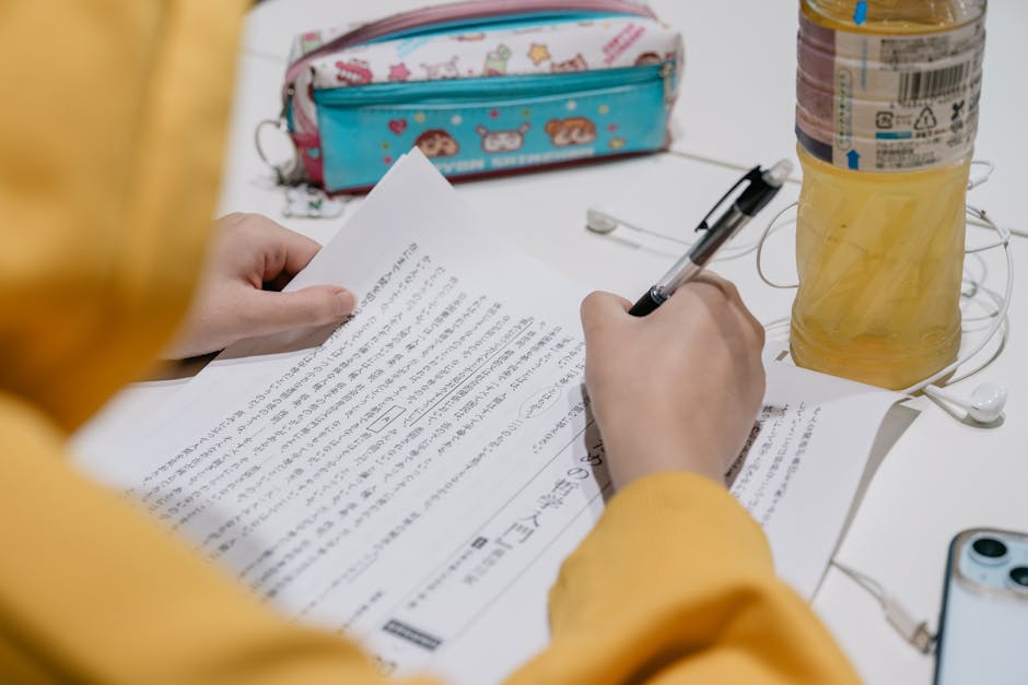 机の上でカラフルな文房具を使いながら日本語のテキストを勉強している人のクローズアップ。