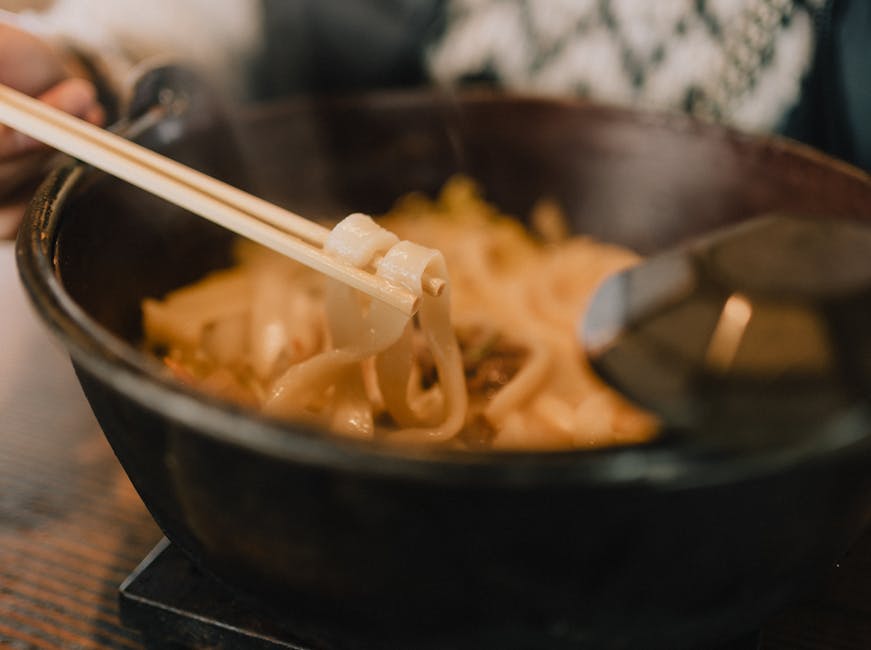 丼に入った湯気の立つうどんと箸のクローズアップ。居心地の良い食事にぴったりです。